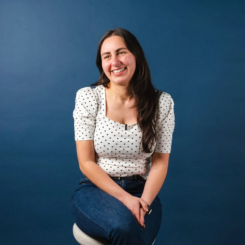 Woman sitting on a stool against a blue background