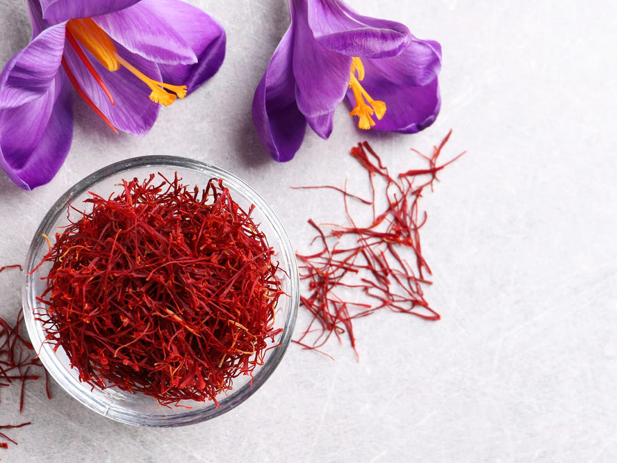 Saffron flowers next to a small bowl of saffron spice