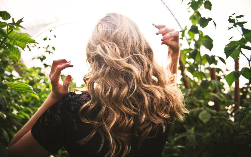 Woman with long hair walking through plants