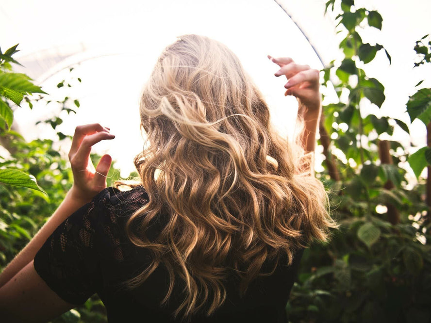 Woman with long hair walking through plants