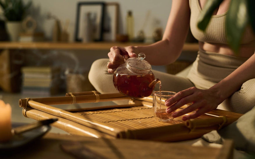 Person sitting crossed legged pouring tea
