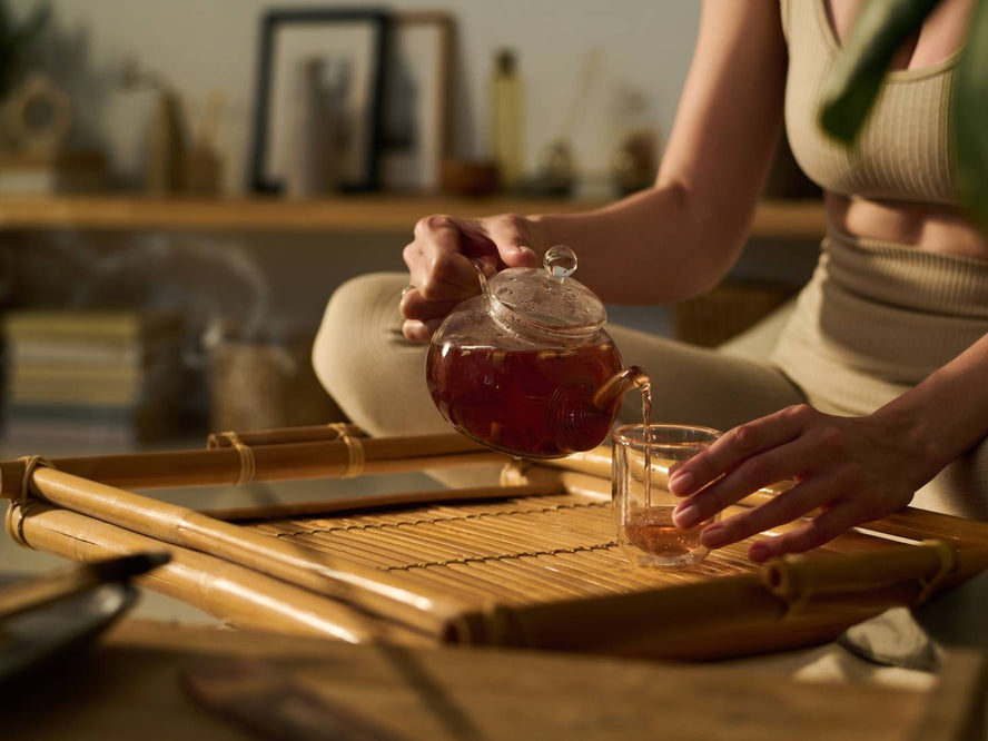 Person sitting crossed legged pouring tea