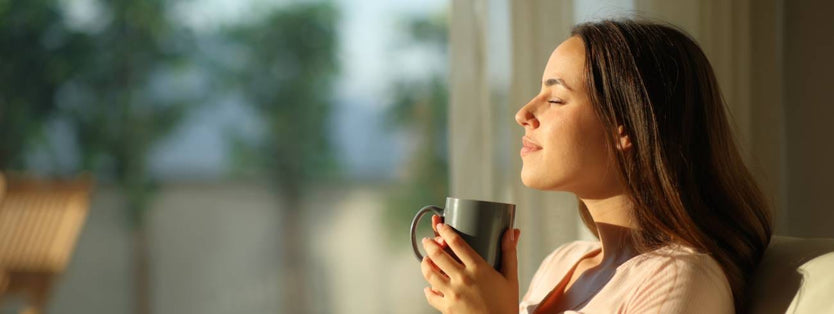 Person drinking a cup of tea in the sunshine