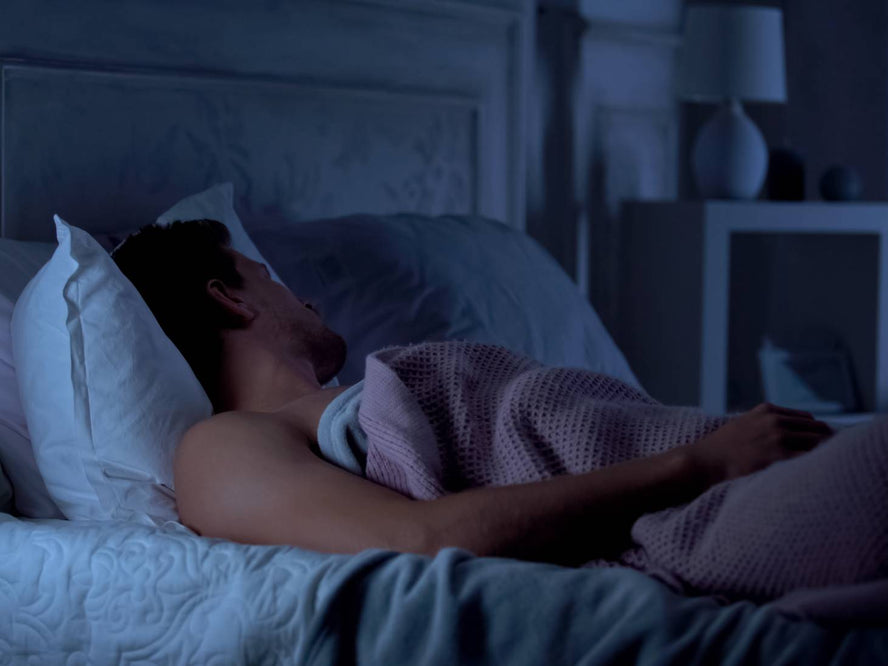 Person in bed asleep in a dark room