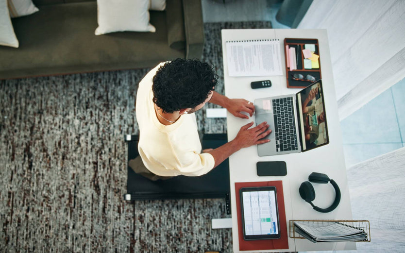 Person working at a stand up desk whilst walking on a walking pad