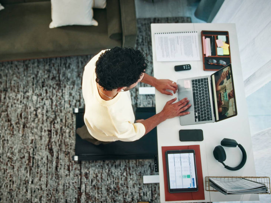 Person working at a stand up desk whilst walking on a walking pad