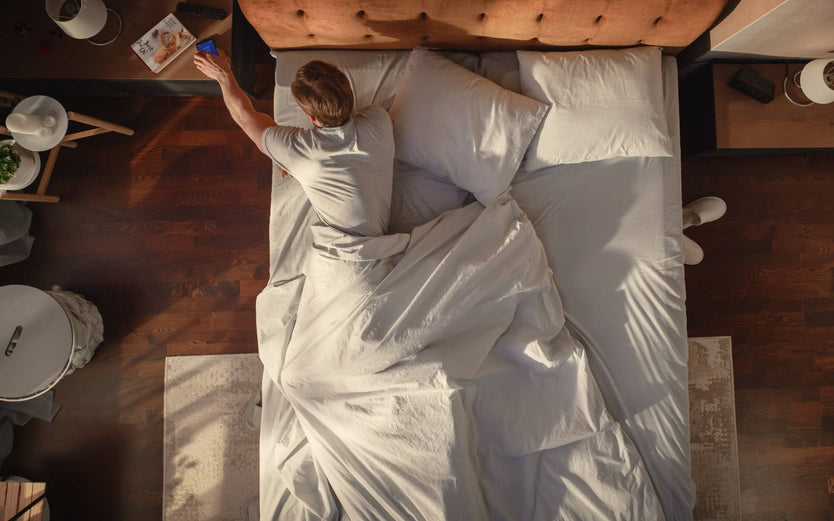 Person in bed reaching to bedside table