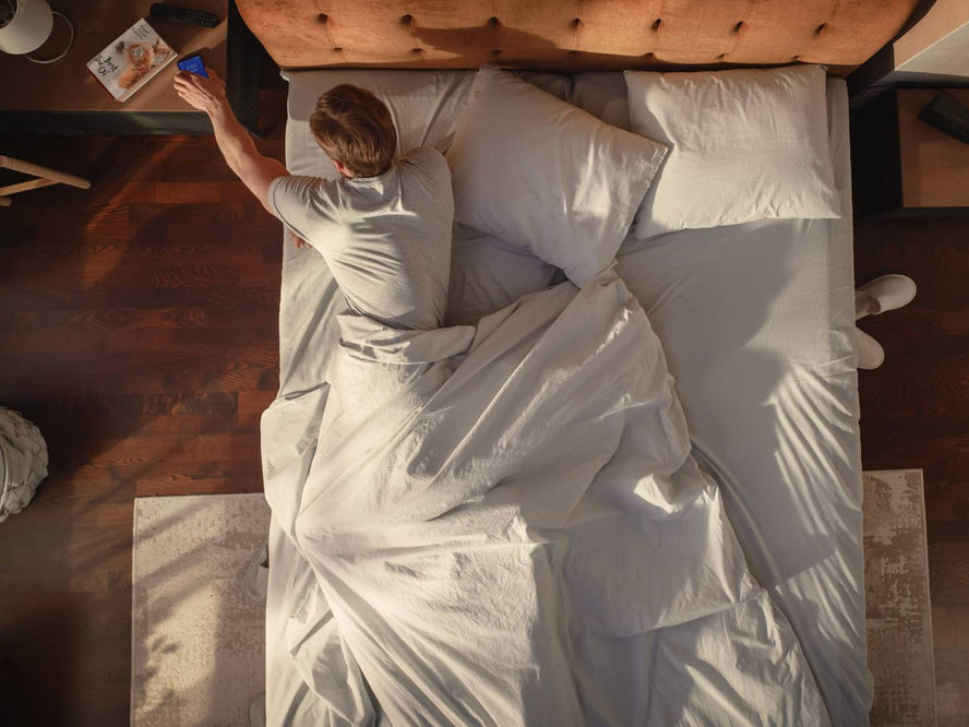 Person in bed reaching to bedside table