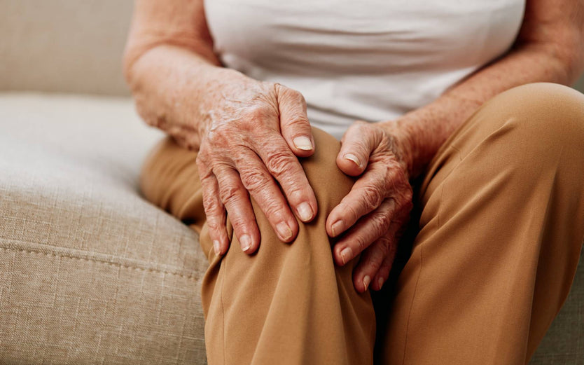 Elderly person holding their knee joint