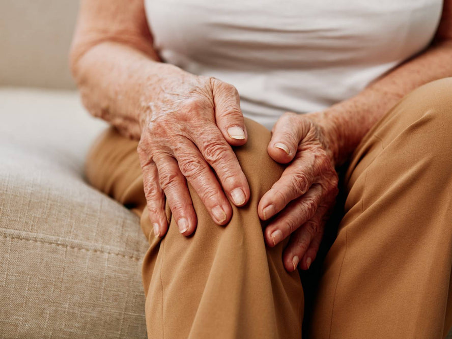 Elderly person holding their knee joint