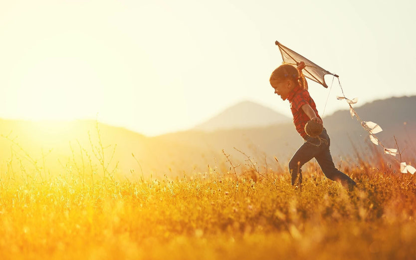 A child running through a field with a kite