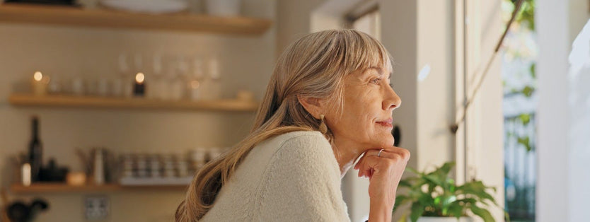 Elderly woman looking out of kitchen window