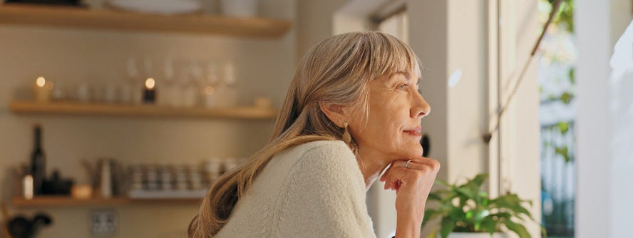 Elderly woman looking out of kitchen window