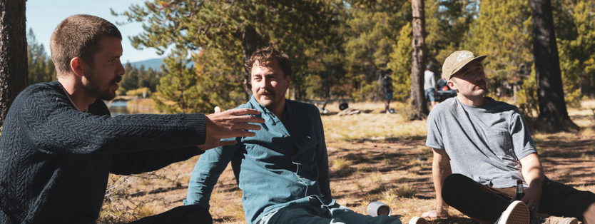 Men sitting on the ground outside talking