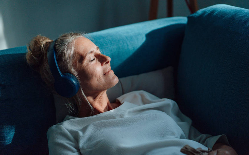 Older woman relaxing on the couch listening to music through headphones