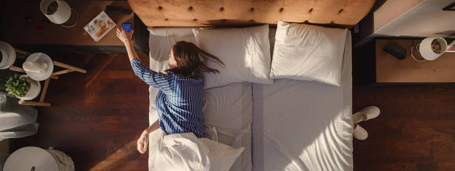Person in bed reaching for alarm