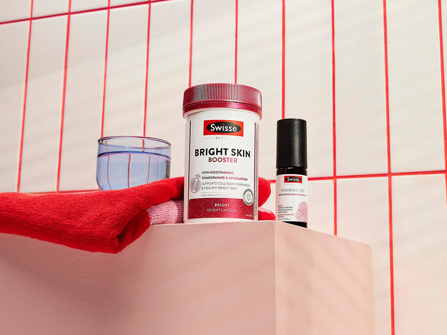 Two Swisse Beauty products from the Bright range next to a red towel and a glass of water.
