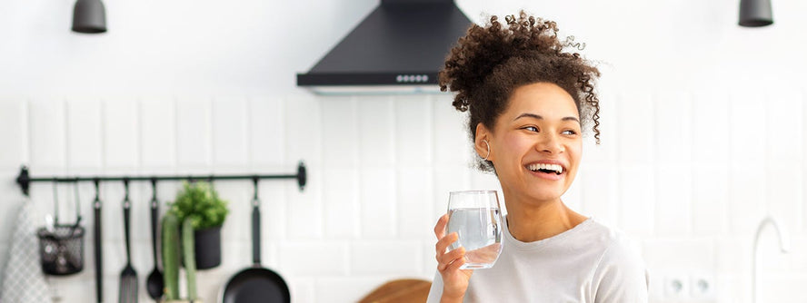 Person drinking a glass of water in the kitchen