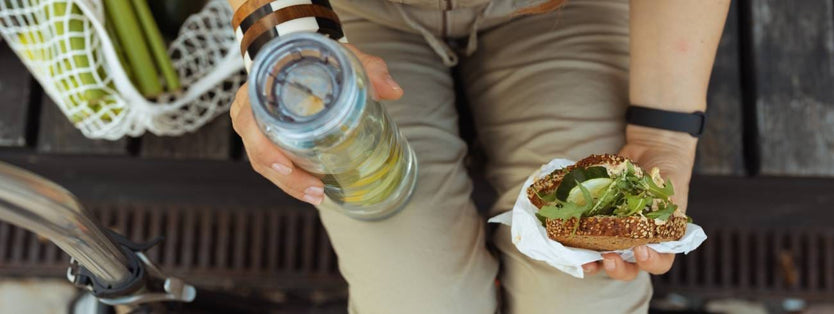 Someone eating a sandwich and holding a bottle of water