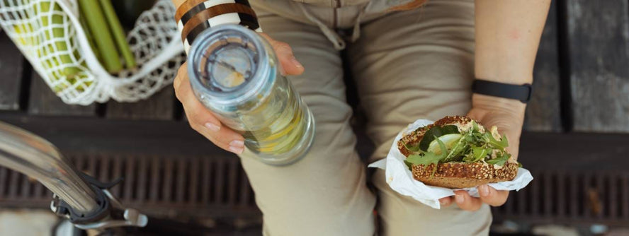 Someone eating a sandwich and holding a bottle of water