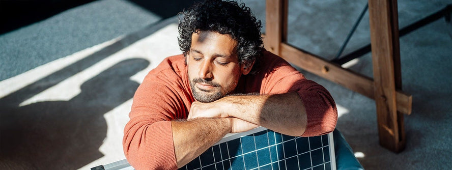 Person sleeping over the back of a chair in the sun
