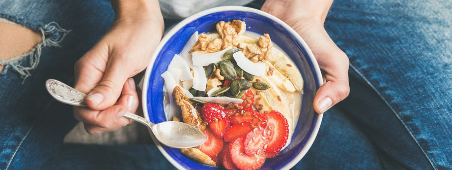 Birdseye view of someone holding a breakfast bowl with cereal and fresh fruit
