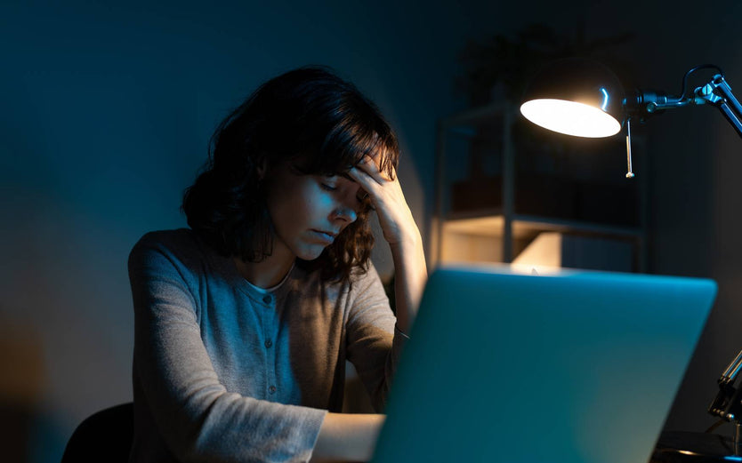 Person sitting behind a computer looking tired