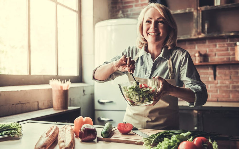 Happy woman making salad in kitchen