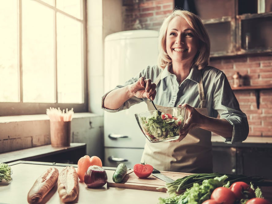 Happy woman making salad in kitchen
