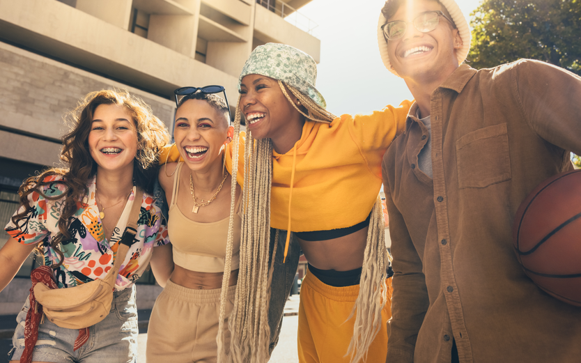 Friends laughing arm in arm in the sunshine