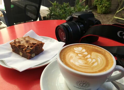Brownie and a cup of coffee on a red table with a camera
