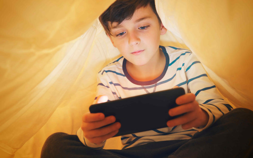 Child playing on phone in a tent