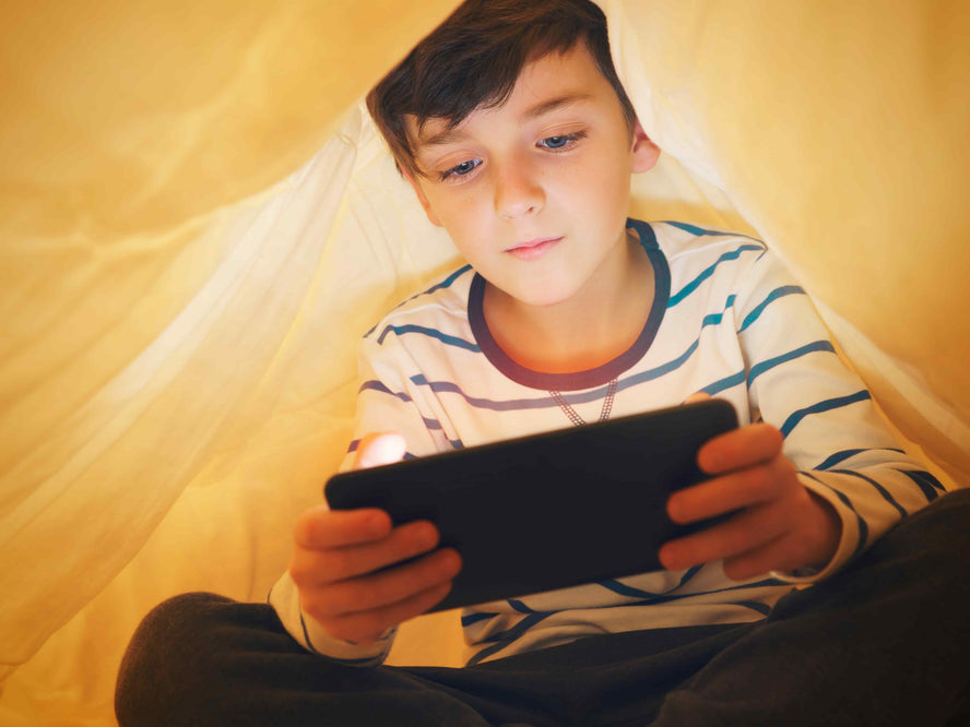 Child playing on phone in a tent