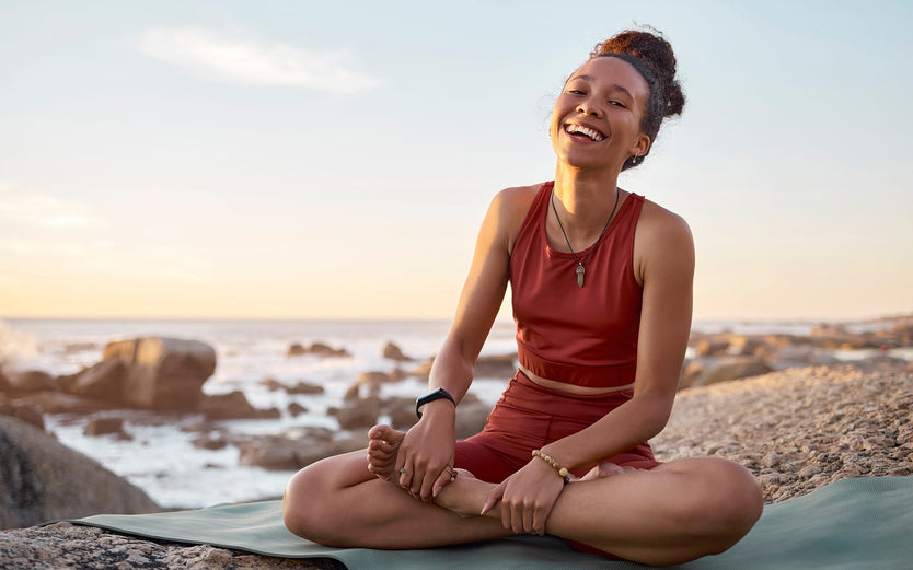 A woman laughing doing yoga on the beach