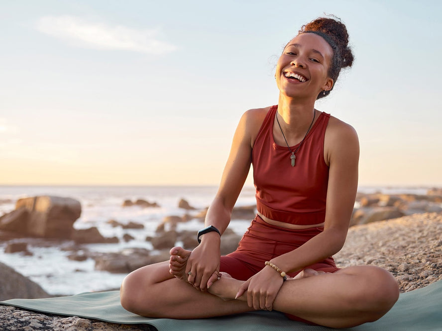 A woman laughing doing yoga on the beach