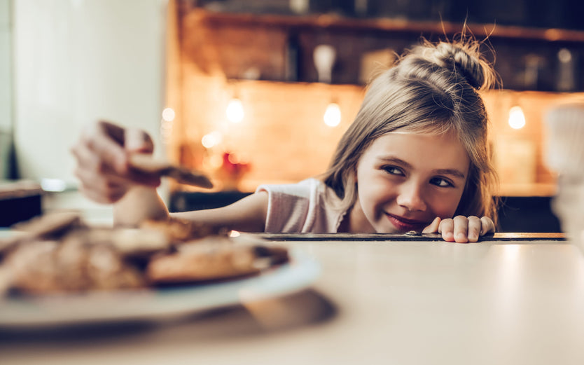 A girl with a plate of cookies in a kitchen