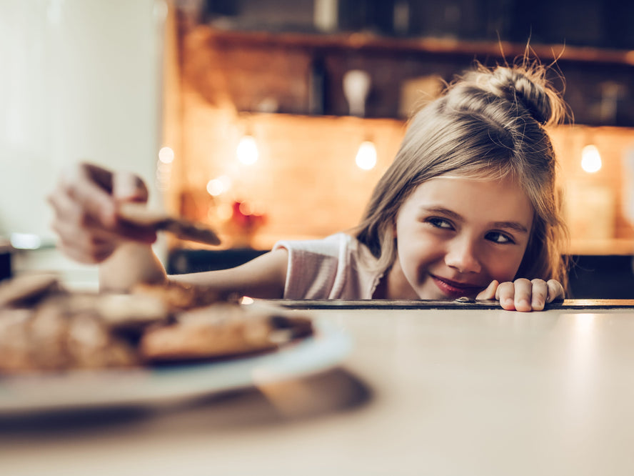A girl with a plate of cookies in a kitchen