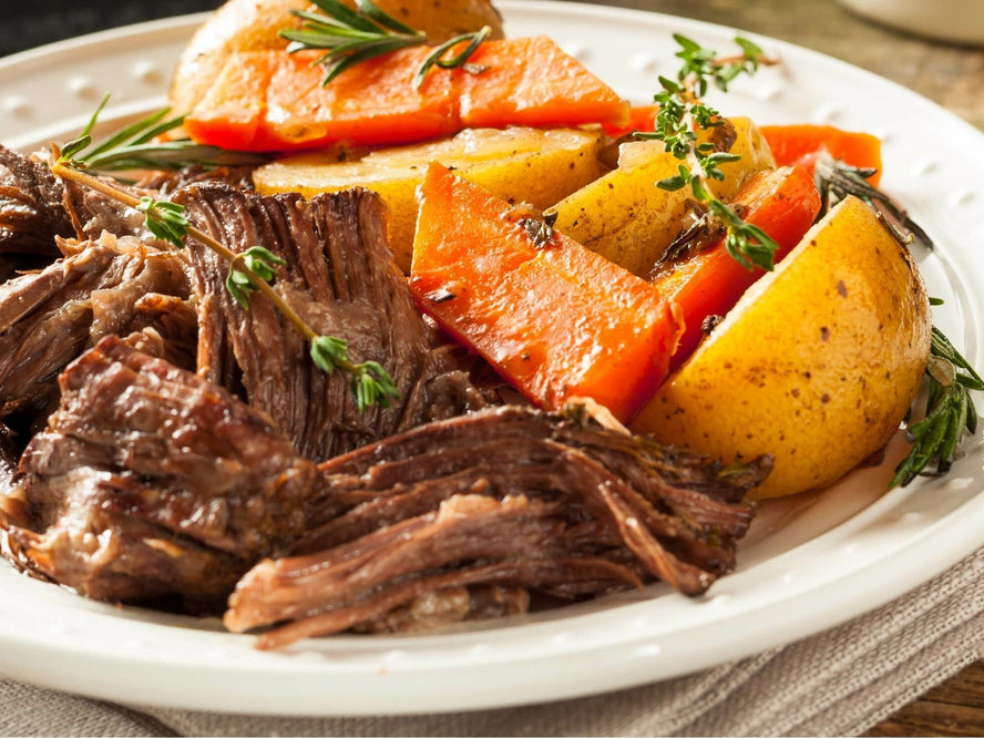 Slow cooked roast beef on a plate with potatos and carrots