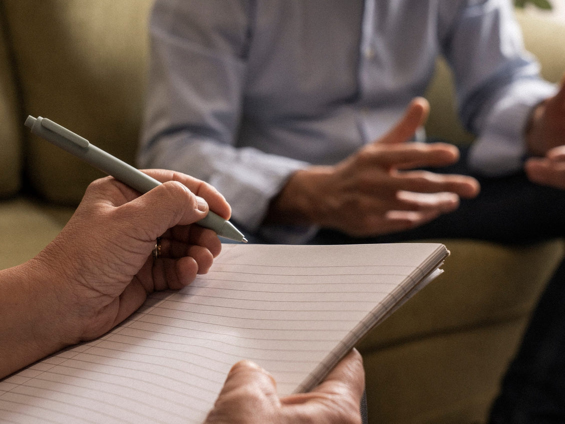Person taking notes during a conversation with another person.
