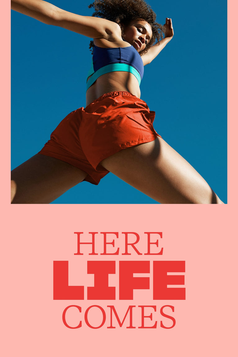 Person in athletic wear with 'HERE LIFE COMES' text on a pink and blue background
