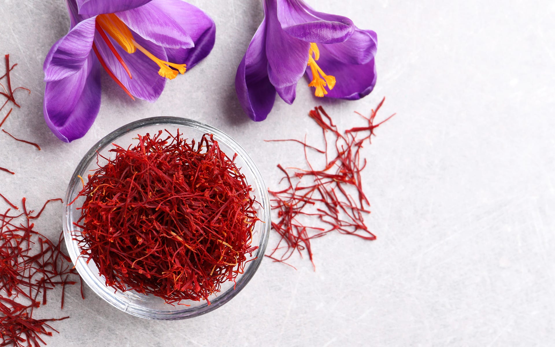 Saffron flowers next to a small bowl of saffron spice