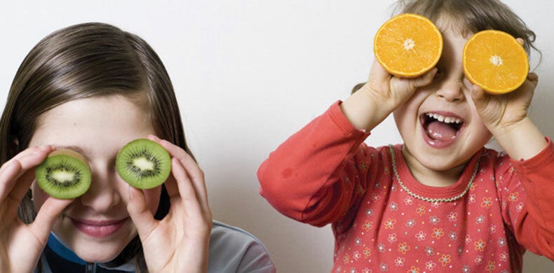 Children holding kiwifruit and oranges