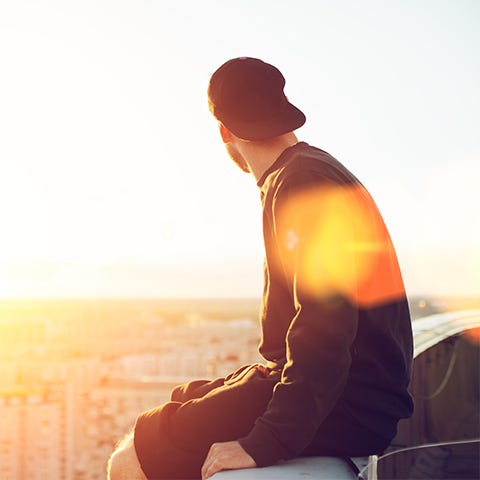 Man sitting on rooftop at sunset