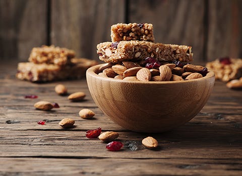 Protein bars and almonds in a wooden bowl