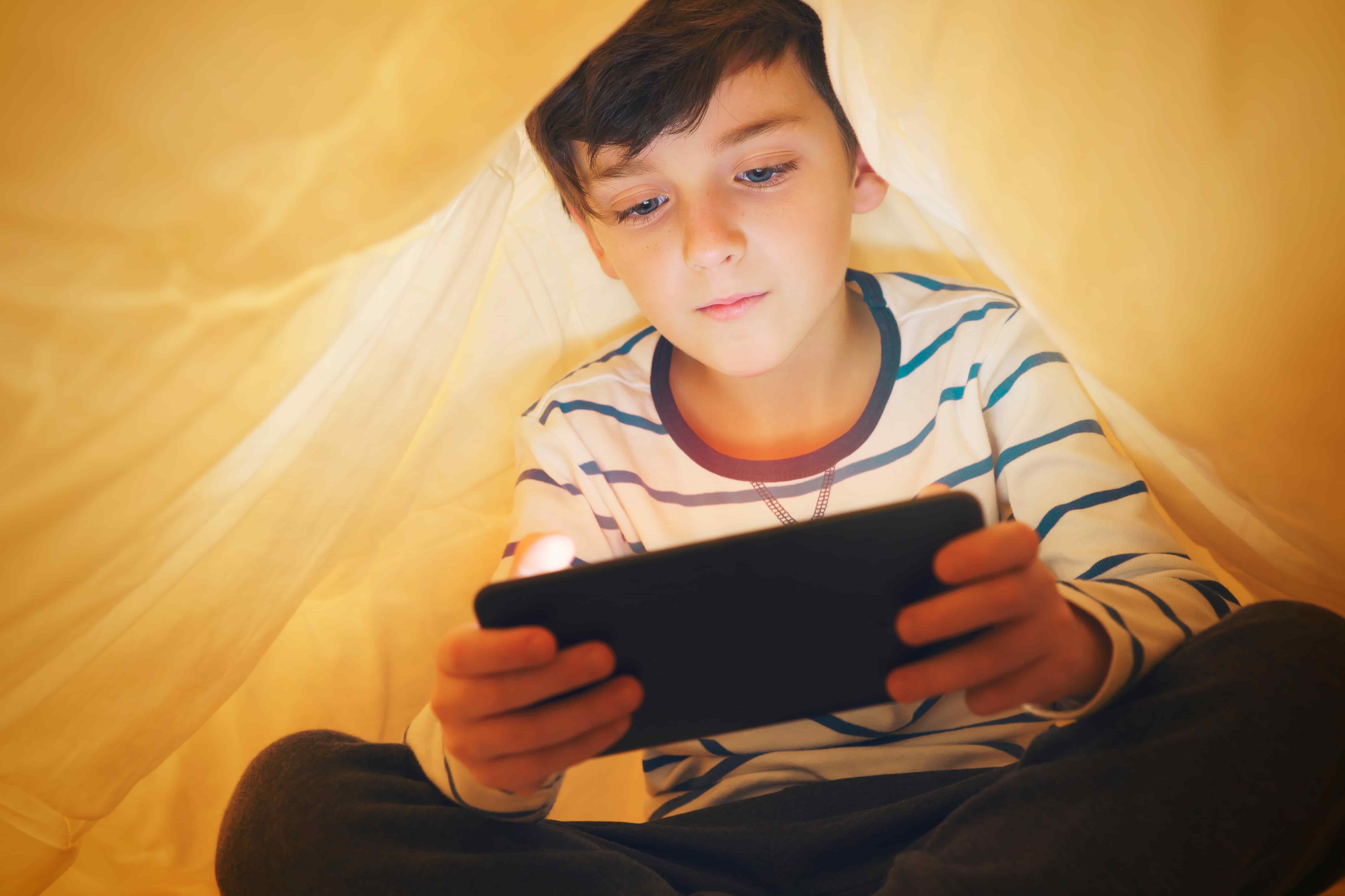 Child playing on phone in a tent
